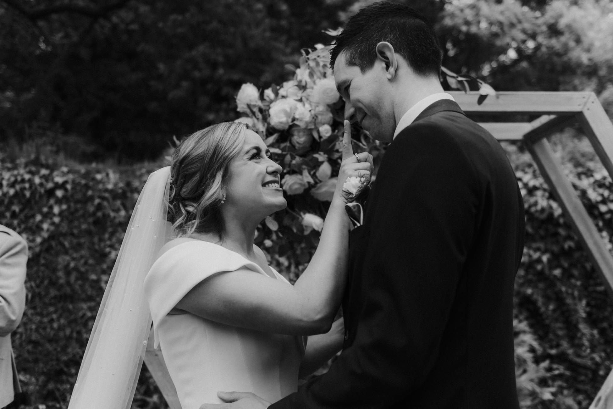 bride touching grooms nose during outdoor wedding ceremony